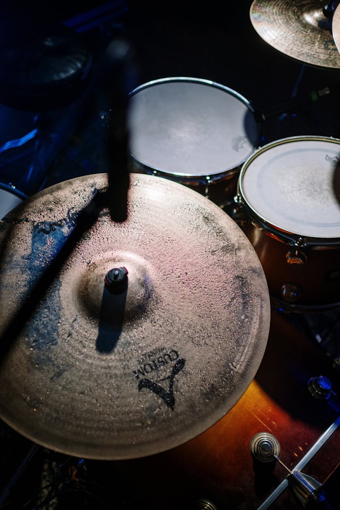 Vertical shot of a drum set focusing on cymbals under low lighting, highlighting texture and mood.