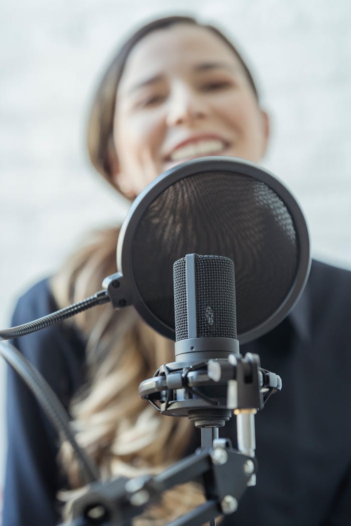 A woman smiles while recording with a professional microphone. Perfect for media and broadcasting themes.